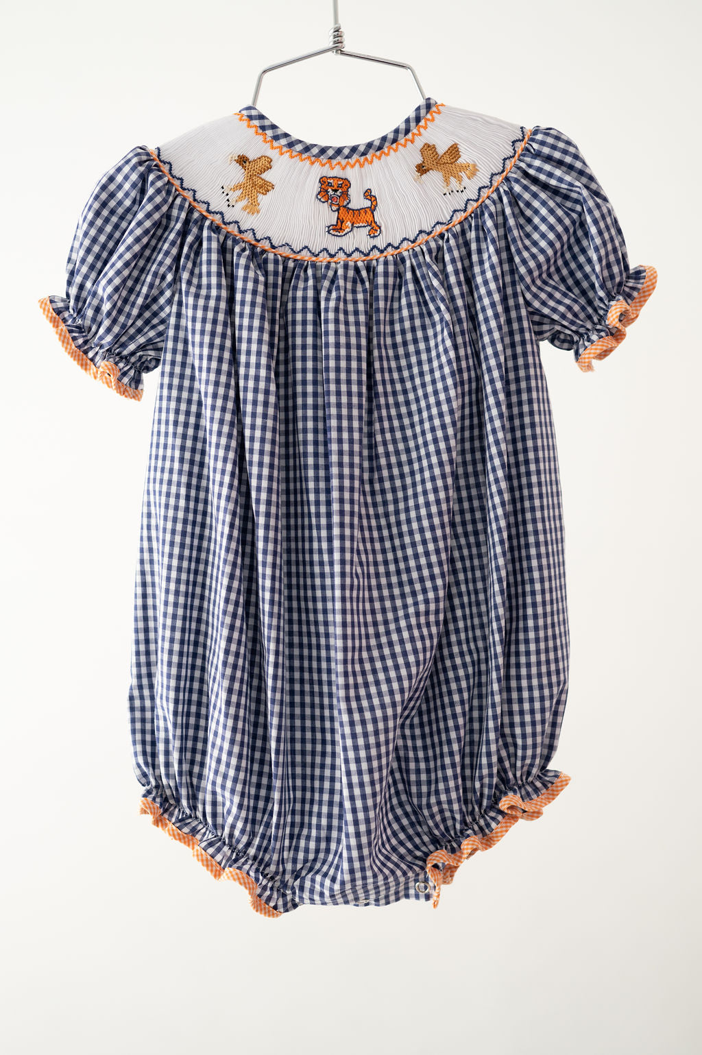 Ruth & Ralph Auburn football smocked girls bubble onesie in navy gingham with orange, tiger, and eagle smocked detail